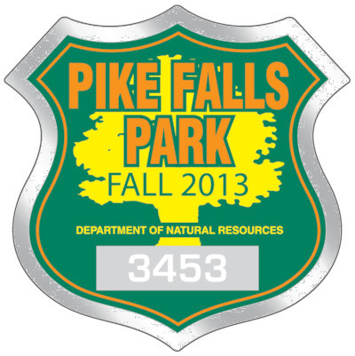 Actual image of our No. 8208 badge shaped parking permits with dimensions of  2 3/4” x 2 3/4” printed with a background color in emerald green and pumpkin orange and primrose yellow text